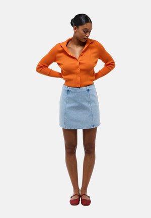 Cardigan côtelé orange avec un col, associé à une mini-jupe en denim bleu clair et des chaussures tissées rouges. Vue à plat, sans motifs ni accents.