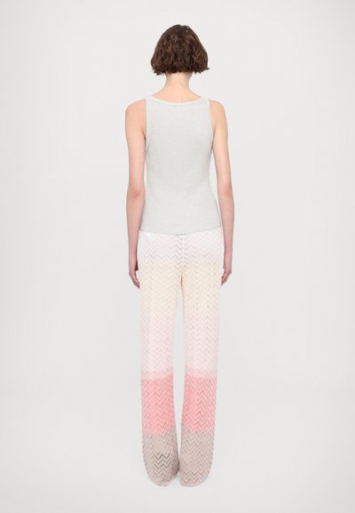 Top sin mangas gris con un diseño ajustado, combinado con pantalones de pierna ancha que presentan un patrón de chevron en tonos pastel de rosa y beige.