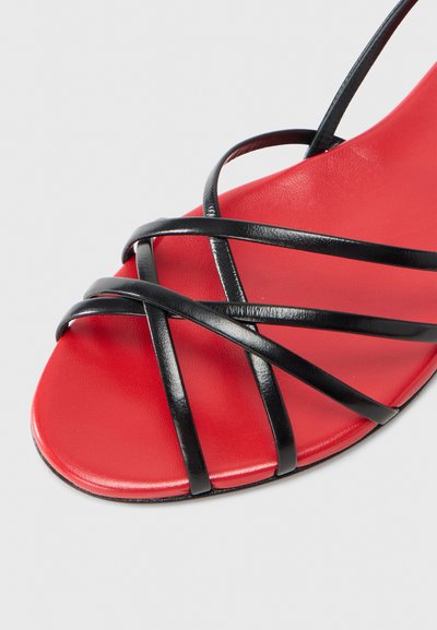 Μαύρο σανδάλι με λουράκια και λεία κόκκινη σόλα, με πολλαπλά διαπλεγμένα λουράκια και μινιμαλιστικό σχεδιασμό. Η σόλα διαθέτει αντιολισθητική υφή.