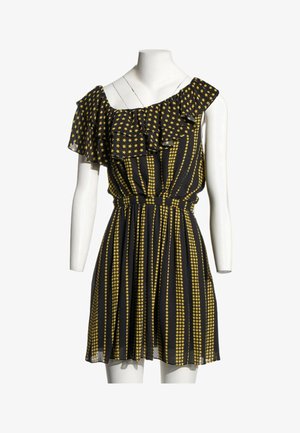 Robe noire sans manches avec motifs d’étoiles jaunes, encolure froncée et taille cintrée, présentée sur un mannequin blanc.
