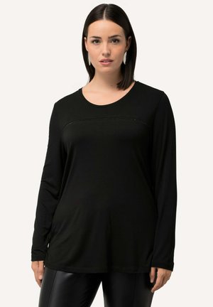 Maglietta nera a maniche lunghe con scollo rotondo, caratterizzata da un pannello testurizzato lungo il petto e tessuto liscio, abbinata a pantaloni neri aderenti e lucidi.