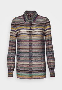 Långärmad skjorta med knappar och ett flerfärgat zigzag-mönster i nyanser av lila, senap, teal, brunt och svart.