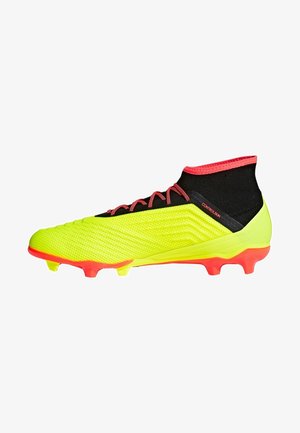 Botas de fútbol de color amarillo brillante con tachones y cordones rojos, cuello negro en el tobillo, diseñadas para jugar en terreno firme.