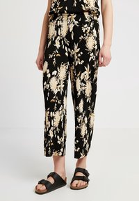 Černé květinové kalhoty s krémovými a žlutými vzory květin, s texturovanou tkaninou, zkrácenou délkou a elastickým pasem. V kombinaci s černými sandály.