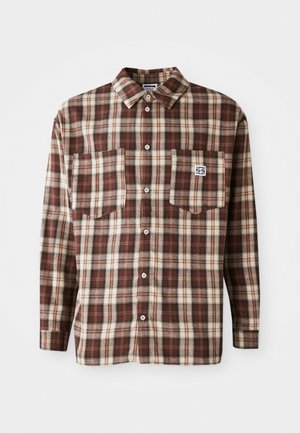 Brown and cream plaid flannel shirt with a collar, long sleeves, two chest pockets, and button closure. Features a brand tag on the pocket.