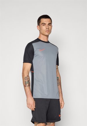 Gray athletic shirt with black sleeves, orange logo accent, round neck, and a fitted design, paired with black shorts.