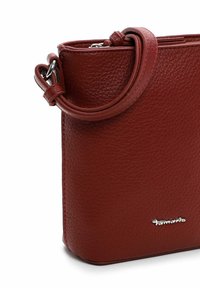 Bolso de piel texturizada roja con una larga correa, forma rectangular y detalle de logo en plata. Acabado suave con acentos mínimos.
