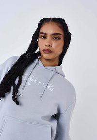 Lichtgrijze hoodie met een voorzak, voorzien van een geborduurd "Project x Paris"-logo in het wit. Verstelbare trekkoorden maken het ontwerp compleet.