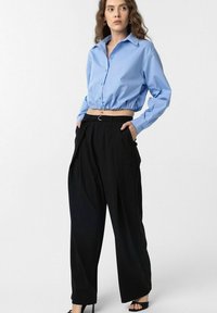 Light blue cropped button-up shirt with a gathered hem, paired with high-waisted black wide-leg trousers, featuring side pockets and a belt.