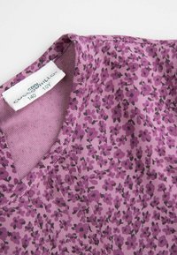 Fioletowa tkanina z kwiatowym wzorem w ciemniejszych odcieniach, z okrągłym dekoltem i widocznymi detalami przeszyć. Obecna metka marki.