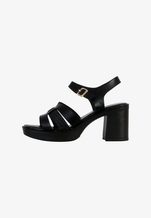 Schwarze Absatzsandalen mit einem offenen Zehenbereich, die drei breite Riemen und einen strukturierten geflochtenen Knöchelriemen aufweisen. Schnallenakzent am Knöchel.