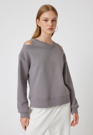 Felpa grigia con design scollo a sorpresa, maniche lunghe e orlo a coste. Realizzata in materiale morbido con una leggera texture e un fit rilassato.