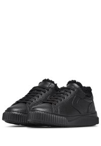 Zwarte sneakers van gestructureerd leer, met een dikke, geribbelde rubberen zool en pluizige zwarte accenten rond de enkel en de tong.