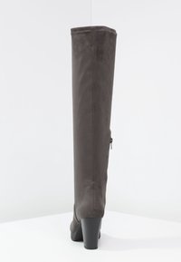 Bota gris de ante por encima de la rodilla con un tacón alto y grueso y cremallera lateral. Textura suave con un ajuste entallado y diseño minimalista.