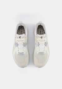 Beige und weiße Turnschuhe mit einem Obermaterial aus Mesh und Wildleder, runder Zehenpartie, Schnürsenkeln und bedruckten Einlegesohlen sowie einer glatten Sohle.