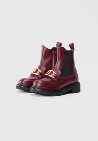 Stivaletti in pelle bordeaux con elastico laterale, dettaglio in oro sulla cintura, suola nera spessa e finitura testurizzata.