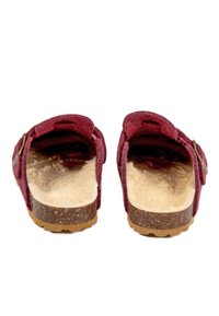 Sabots slip-on en feutre bourgogne avec une semelle intérieure beige texturée, une semelle en liège et une sangle en cuir ajustable avec un détail de boucle en métal.