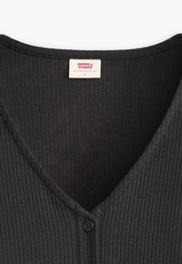 Cardigan noir à côtelé avec décolleté en V, présentant un détail de bouton unique et une étiquette portant "Levi's, San Francisco, CA, S."
