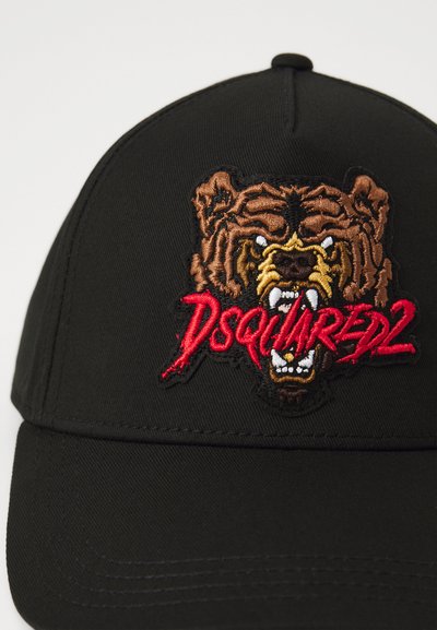 Svart keps med broderad brun björnsans och röd "DSQUARED2"-logotyp. Materialet är slätt med en strukturerad form och justerbar rem.