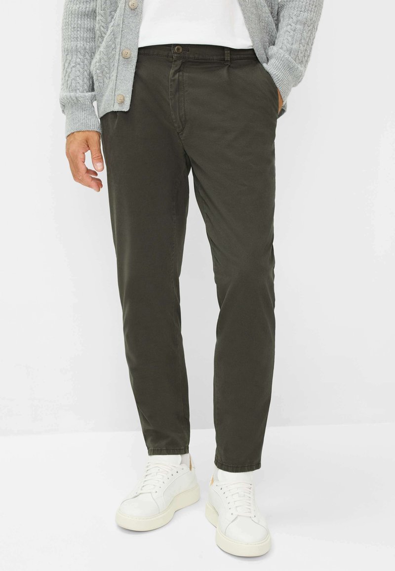 Olijfgroene slim-fit broek van katoenmix stof, met zijzakken en een knoopsluiting, gecombineerd met witte sneakers.