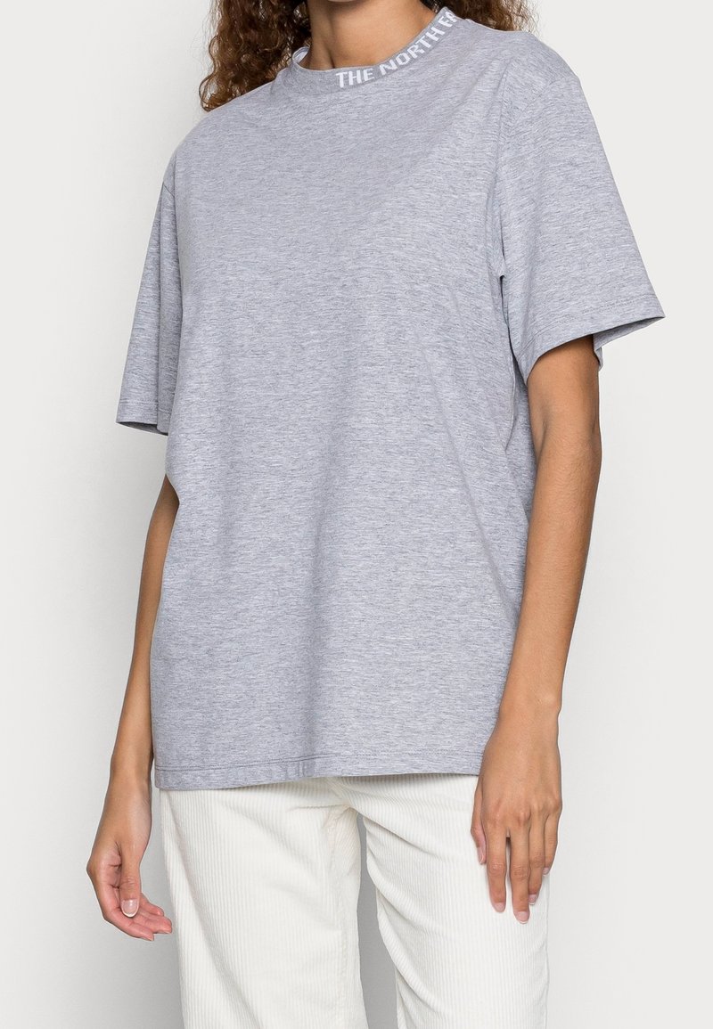Grå bomullströja med korta ärmar och rundad halsringning, med texten "THE NORTH" på kragen. Rak skärning och slät textur.