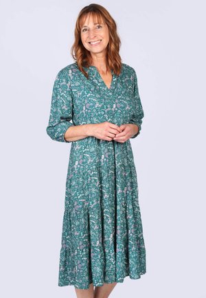 Blumendruckkleid in Türkis mit V-Ausschnitt, Dreiviertelärmeln und gestuftem Rock. Verfügt über rosa und weiße Blütenmuster.