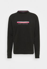 Sudadera negra con cuello redondo y mangas largas estilo raglán. Presenta un logo a rayas en blanco, rojo y azul en el pecho. Tejido suave.