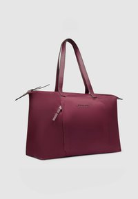 Bordeauxrode draagtas gemaakt van glad stof met twee lange handvatten, een ritssluiting en twee buitentassen. Voorzien van een merklogo aan de voorkant.