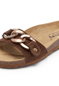 Sandale en suède marron avec une large lanière ornée d'une chaîne métallique, semelle intérieure marron et semelle en caoutchouc texturée pour une meilleure adhérence.