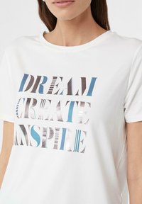 Weißes Baumwoll-T-Shirt mit Rundhalsausschnitt und kurzen Ärmeln, verziert mit metallischer und blauer Typografie: "TRÄUMEN, KREIEREN, INSPIRIEREN."