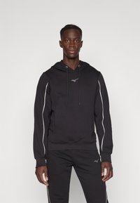 Black hoodie with a drawstring, long sleeves, and white side stripes. Soft material with a logo on the chest and matching black pants.