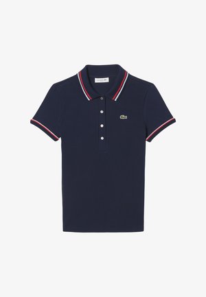 Polo en coton bleu marine avec un col et des ourlets de manches rayés rouge et blanc, présentant une patte de boutonnage à cinq boutons et un logo vert sur la poitrine.