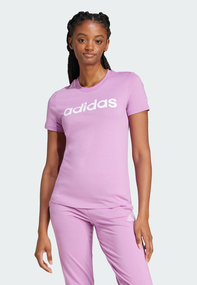 Jasnoróżowy bawełniany t-shirt z krótkimi rękawami i okrągłym dekoltem. Na przodzie znajduje się wyraźne, białe logo „adidas”.