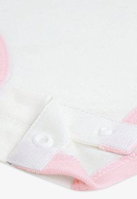 Λευκό βαμβακερό πουκάμισο με ροζ λεπτομέρειες, κούμπωμα με κουμπιά και υφή υφάσματος. Σημαντικές λεπτομέρειες περιλαμβάνουν ροζ ραφές και αντίθετες άκρες γιακά.