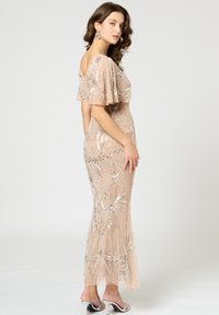Beadbesetztes Abendkleid in zartem Rosé mit einer figurbetonten Silhouette, flatternden Ärmeln und filigranen silbernen Blattmustern. Durchscheinender Stoff mit weicher Textur.