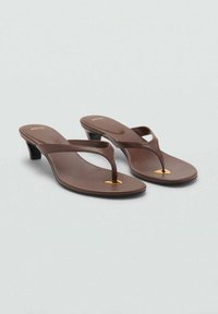 Braune Flip-Flop-Sandalen mit einem niedrigen, geschwungenen Absatz, ausgestattet mit einem dünnen Riemen und einem kleinen goldenen Akzent am Zehensteg. Glatte Textur.