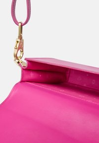 Interno di una borsa in pelle rosa, caratterizzato da una texture liscia, una chiusura in hardware dorato e un motivo goffrato sottile sulla fodera.