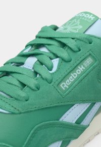 Zaļi un gaismas zili sporta apavi ar zamša augšdaļu, ar teksturētu dizainu, Reebok zīmolu un saskaņotām šņorēm.