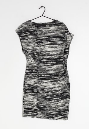 Robe noir et blanc accrochée à un crochet, présentant un motif abstrait texturé avec des manches courtes et une coupe ajustée.