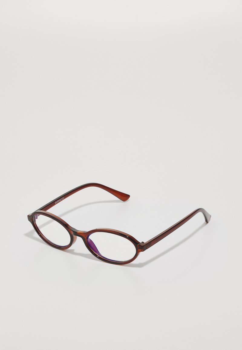Lunettes ovales brunes avec des verres teintés de violet, en plastique. Branches fines et droites, avec une texture subtile et un branding minimal.