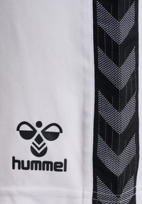 Weiße Sportshorts mit einem schwarzen Chevron-Muster an der Seite und einem schwarzen "hummel"-Logo am unteren Ende. Hergestellt aus strukturiertem Stoff.