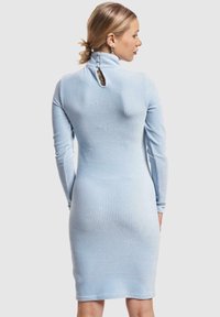 Hellblau gestricktes Kleid mit hohem Kragen und langen Ärmeln. Verfügt über einen Schlüsselloch-Ausschnitt auf der Rückseite und Knöpfe entlang des Kragens. Weiche Textur.