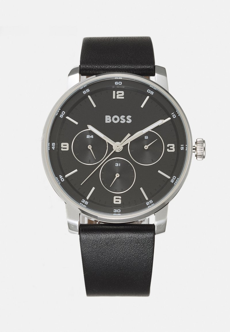Reloj con correa de cuero negro, caja redonda de plata, esfera negra con tres subesferas y marcadores y manecillas de horas en plata.