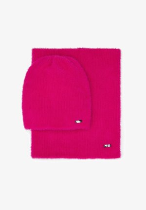 Ensemble bonnet et écharpe en tricot rose duveteux. Le bonnet a un sommet arrondi ; l'écharpe est rectangulaire avec une texture douce. Comprend de petits accents en métal argenté.