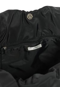 Intérieur d'un sac en nylon noir avec une poche zippée et une étiquette en tissu blanc portant la mention "InWear" cousue à l'intérieur.