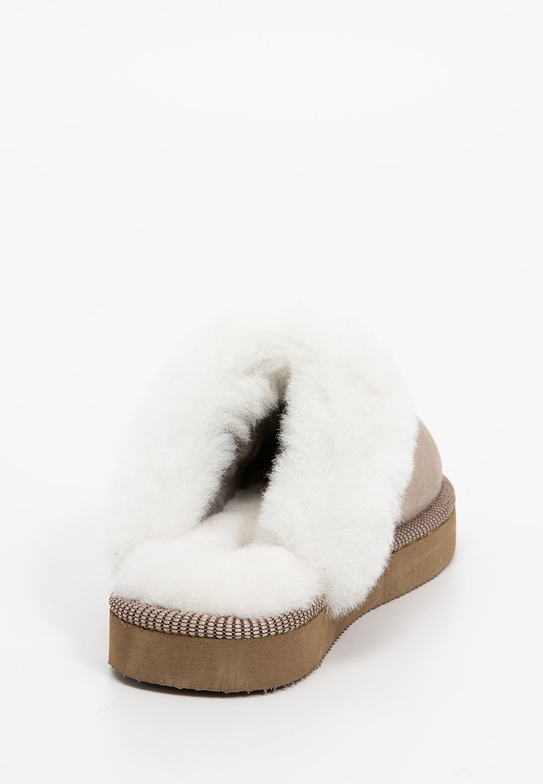 Pantofole in suede marrone con fodera in shearling bianco, apertura sul retro e suola testurizzata. Presenta un plantare imbottito per il massimo comfort.