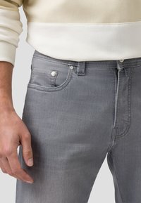 Grijze denim jeans met een klassiek vijf-pocket ontwerp, zilveren hardware en subtiele wassing. Gekocht met een crèmekleurige sweatshirt.