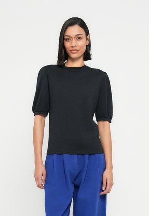 Zwart kort mouwtje top met opgeblazen mouwen, ronde hals en zachte textuur, gecombineerd met losse blauwe broek. Minimalistisch ontwerp.