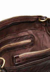 Interno della borsa in pelle marrone con zip dorate, presenta numerosi scomparti e una superficie liscia. Cuciture dettagliate visibili.