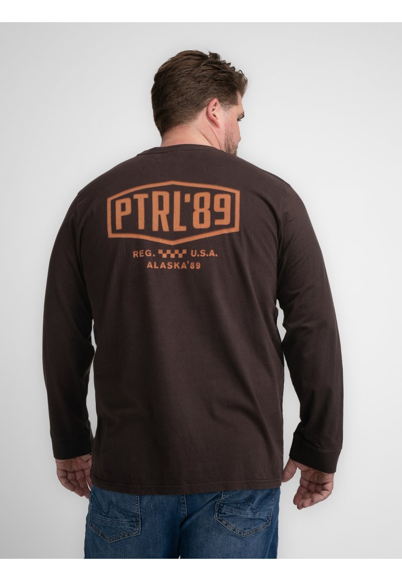 Brown overhemd met lange mouwen van katoen, voorzien van een groot oranje geprint ontwerp op de achterkant met de teksten "PTRL'89" en "ALASKA'89".